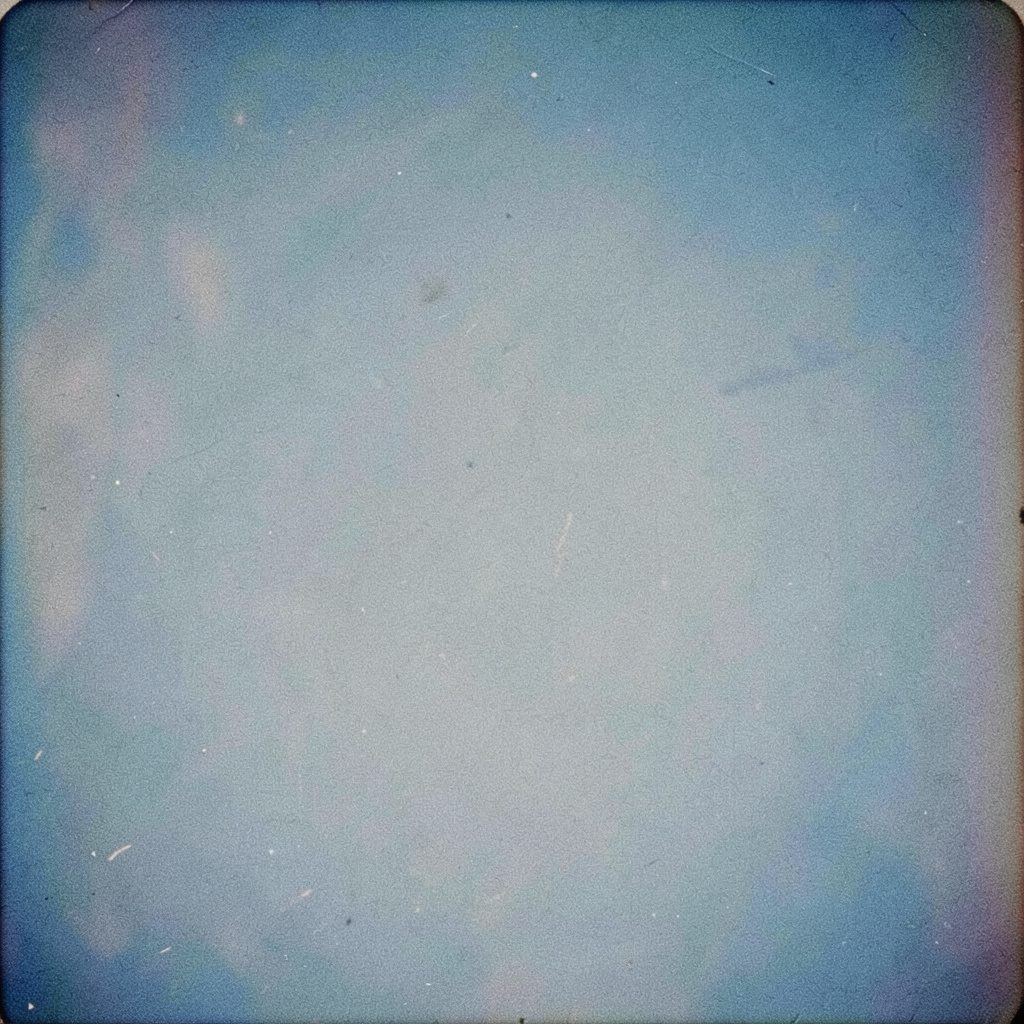 Analog film photograph of stacked printed conference papers and a fountain pen on warm wooden desk, cyanotype blue tones, visible grain